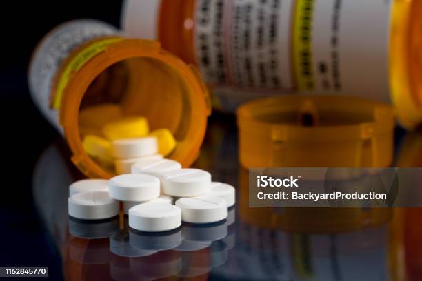 Macro Of Oxycodone Opioid Tablets With Prescription Bottles Against Dark Background Stock Photo - Download Image Now