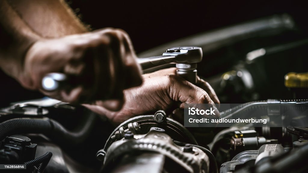 Auto mechanic working on car engine in mechanics garage. Repair service. authentic close-up shot Car Stock Photo