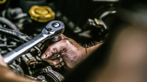 Auto mechanic working on car engine in mechanics garage. Repair service. authentic close-up shot stock photo