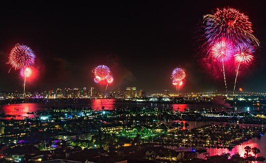 Multi-colored fireworks over San Diego Bay at night on Fourth of July with skyline in background