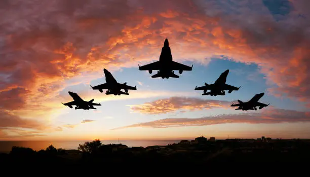 Five fighters flying at sunset