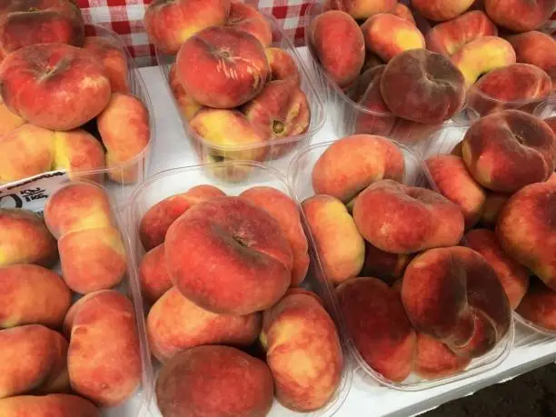 Photo of Boxes of saturn peaches sold at a market in Croatia.  The flat peach (Prunus persica var. platycarpa), also known as the doughnut peach or Saturn peach, is a variety of peach with pale yellow fruit.