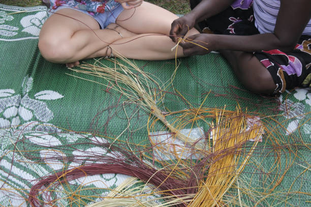 Aboriginal basket weaving Indigenous Australians aboriginal woman teaching a tourist Aboriginal basket weaving technique. australian aborigine culture stock pictures, royalty-free photos & images