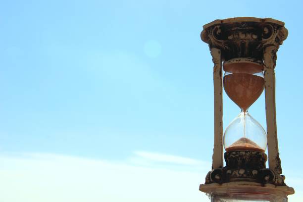 istock retro hourglass on the background of blue sky and white clouds 1162872596