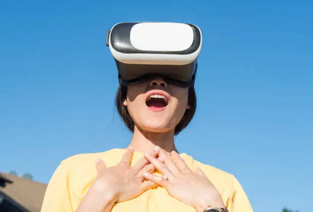 Photo of Portrait of young Asian woman wearing virtual reality goggles and enjoying the VR simulation experience.