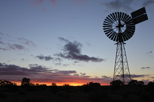 Silhouette of a large windmill in central Australia outback during a dramatic sunset.