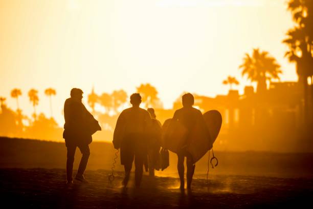 bodyboarders leaving the beach at sunset Newport Beach, Ca - July 5, 2018: a group of body boarders leaving The Wedge in Newport Beach during sunset newport beach california stock pictures, royalty-free photos & images