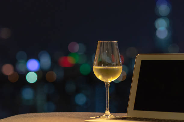 un bicchiere con vino bianco mette sul divano con computer portatile. - glass bar relaxation red foto e immagini stock