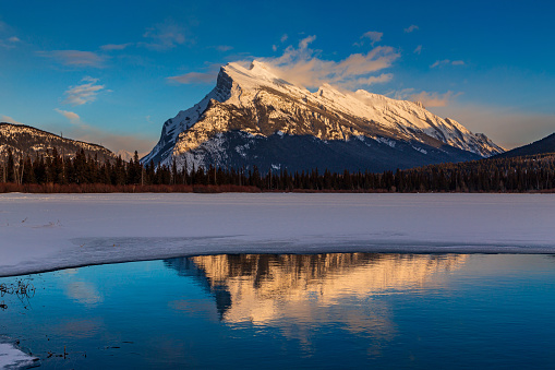 Reflection of Mt. Rundle in largely frozen Lake Vermilion near the Town of Banff, Alberta, Canada.