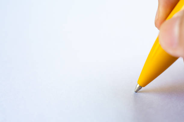 istock Woman's right Hand holding a yellow pen, writing letter on white paper background, Notebook, Close up & Macro shot, Selective focus, Communication, Stationery concept 1162885556