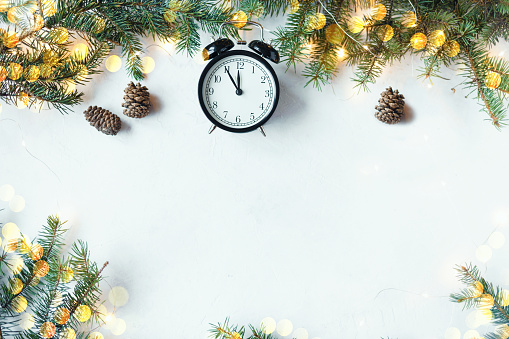 Christmas festive background. Fir branches, garlands, New Year's toys on a wooden background Christmas alarm clock 23:55 , cookies, festoon on a light background Banner