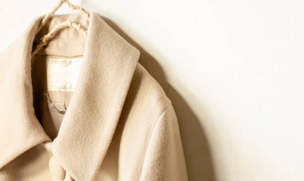 istock beige wool coat hanging on clothes hanger on white background 1162895894