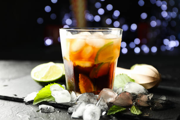 istock Glass with cola and lime slices, juicer, ice, mint against blurred lights background 1162905592