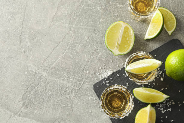 istock Tequila shots with salt and lime slices on grey background 1162910279