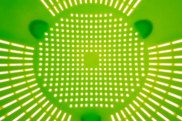 Close-up of a green plastic colander, a kitchen utensil to drain pasta, on a white background