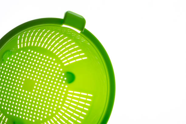 Close-up of a green plastic colander, a kitchen utensil to drain pasta, on a white background. Photo with copy space.