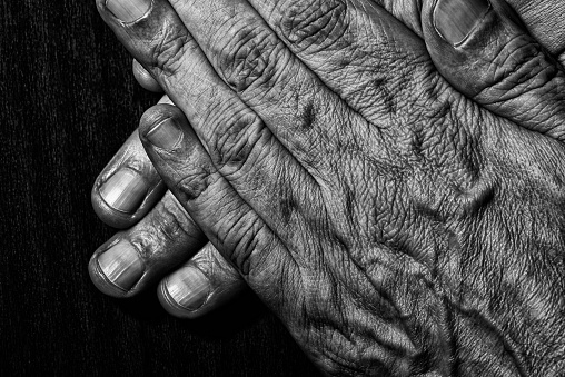 Black and White photo of senior man crossed hands detail on dark background