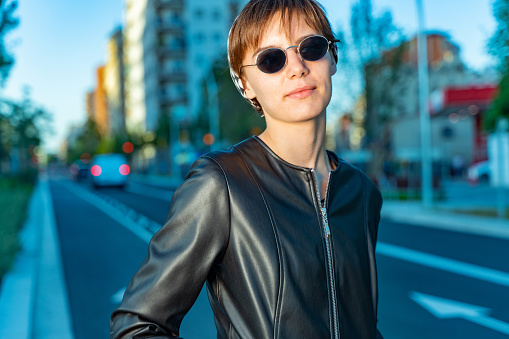 Young girl wearing a black leather jacket, crossing the street in Barcelona.