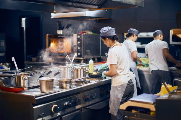 l'équipe de cuisiniers soutient dans le travail dans la cuisine moderne, le flux de travail du restaurant dans la cuisine. copier l'espace pour le texte - work equipment photos et images de collection