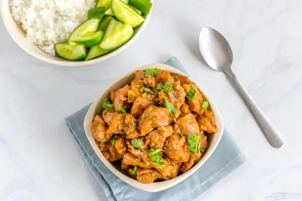 Chinese Style Stir-Fried Chicken with Rice and Cucumber in the Bowls Directly Above Photo.