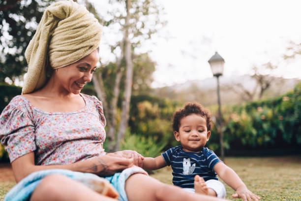 Affectionate young African descendant mother spending time outdoors with her baby son