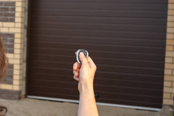 mano con mando a distancia abre la puerta de garaje seccional automático - automático fotografías e imágenes de stock