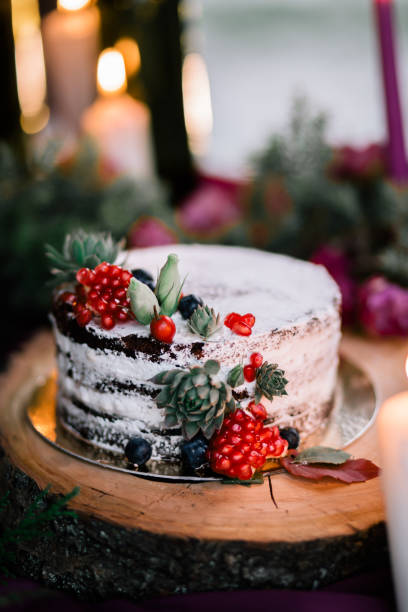 istock Delicate wedding white cake decorated with pomegranate and succulent surrounded by flowers and candles. 1162916004