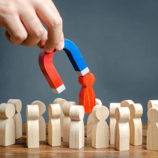 istock The hand with a magnet pulls out a red figure of a man from the crowd. Increase team efficiency, productivity. leader manages the business and forms a team. toxic, incompetent worker. 1162924491