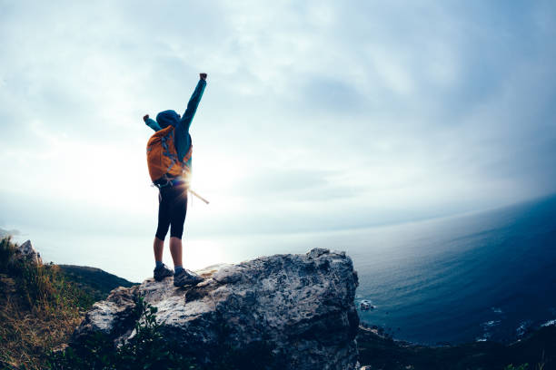 istock Successful hiker outstretched arms at seaside mountain top cliff edge 1162924525