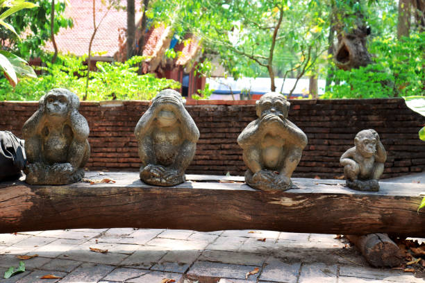 istock Three monkey statue sit on nature background and hand small statues with the concept of see no evil, hear no evil and speak no evil 1162924630