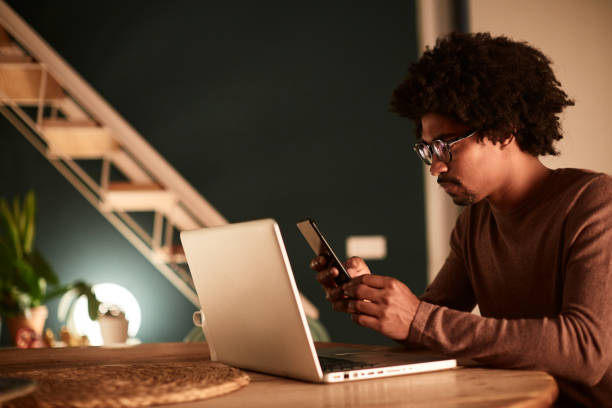 istock Young man working late at home, sending an sms with a mobile phone. 1162928073
