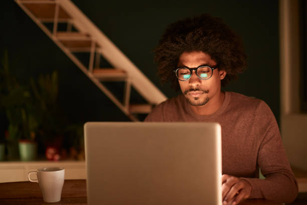 istock Young man working late at home, surfing the net at night. 1162928076