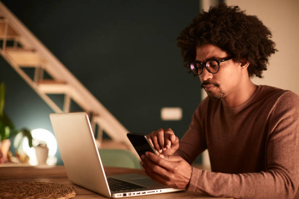 istock Young man working late at home, sending an sms with a mobile phone. 1162928080