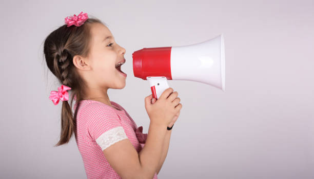 istock Child Girl Shouting Through Megaphone on Grey Background. Communication and Advertising Concept. 1162933174