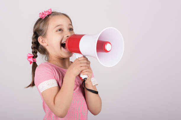 istock Child Girl Shouting Through Megaphone on Grey Background. Communication and Advertising Concept. 1162934175