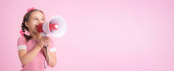 child girl shouting through megaphone on pink background. communication and advertising concept. - marketing megaphone child using voice imagens e fotografias de stock