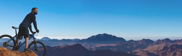 Cyclist in shorts and jersey on a modern carbon hardtail bike with an air suspension fork riding in the mountains in the evening red sunset stock photo