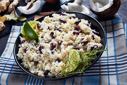 close-up of Jamaican Rice and Red Beans cooked with coconut milk seasoned with garlic, onions and creole spice in a bowl with ingredients at the background