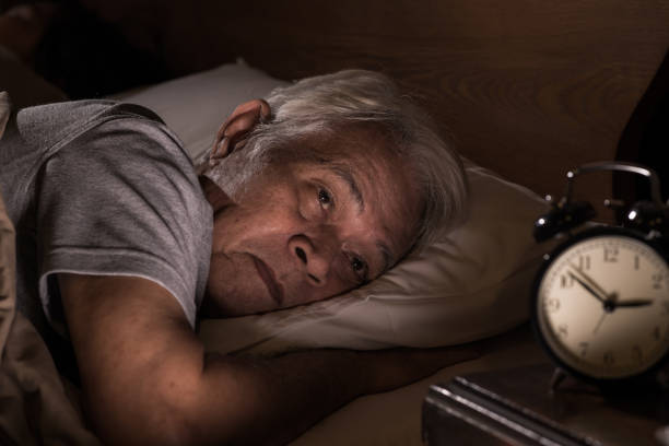 a depressed senior man lying in bed cannot sleep from insomnia - insomnia imagens e fotografias de stock