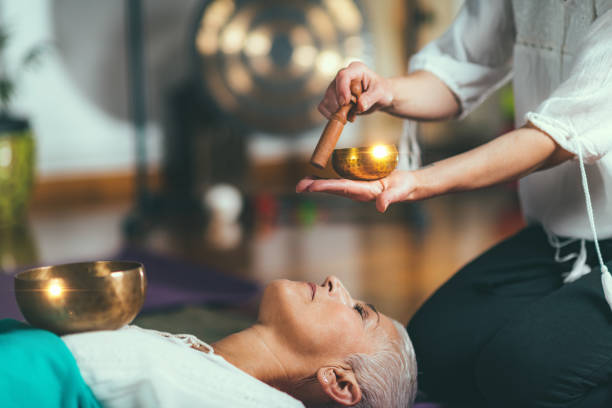 Midsection Of Woman Playing Singing Bowl For Customer In Spa  tibet culture stock pictures, royalty-free photos & images