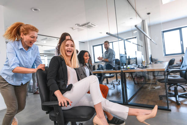 istock Playful Business Colleagues Racing Chairs Through Office 1162941482