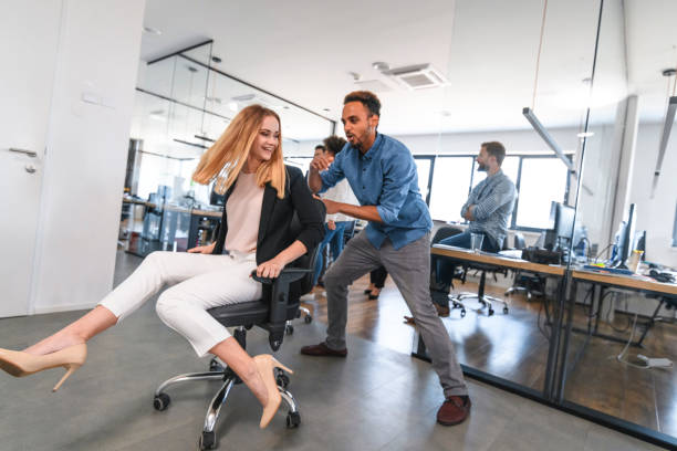 istock Carefree Business Colleagues Racing Chairs Through Office 1162941492