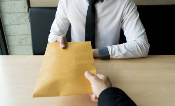 istock Cropped Hand Giving Brown Envelope To Businessman At Table 1162941589