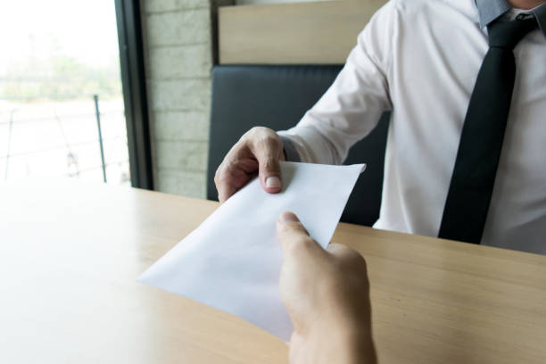 istock Cropped Hand Giving Envelope To Businessman At Table 1162941590