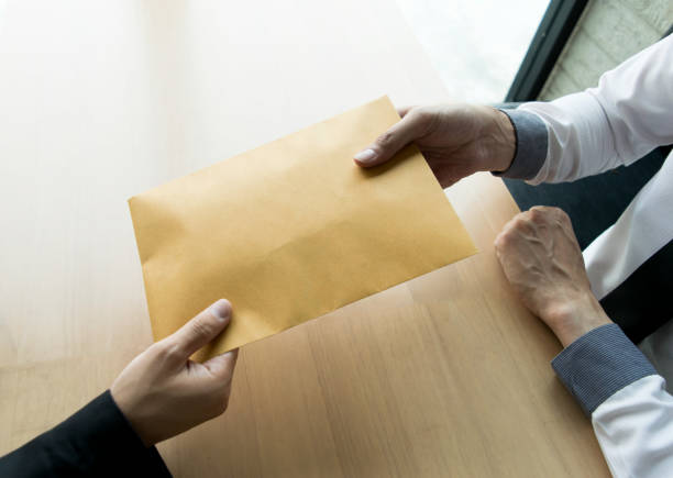 istock Cropped Hand Giving Envelope To Businessman At Table 1162942574