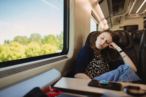 A girl is sleeping on a train as she travels to her next destination in Italy.