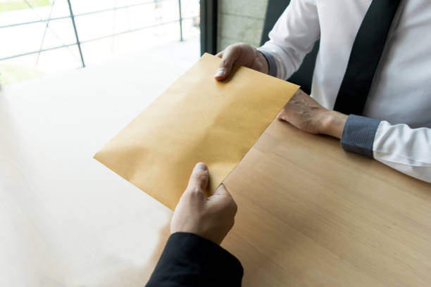 istock Cropped Hand Giving Envelope To Businessman At Table 1162944948
