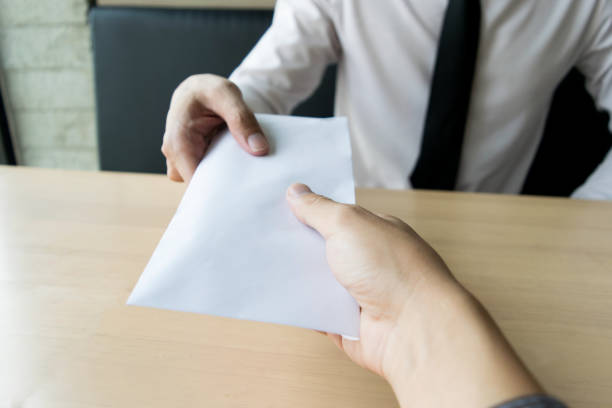 istock Cropped Hand Giving Envelope To Businessman At Table 1162946610
