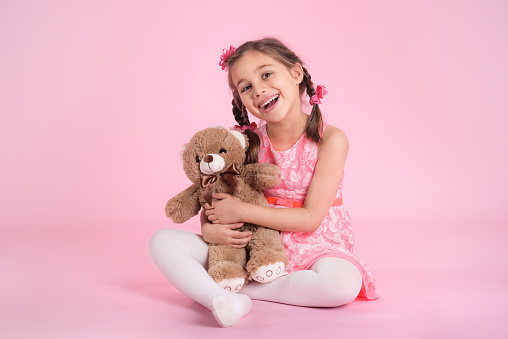 Portrait of Child Girl Hugging Her Soft Toy Bear on Pink Background