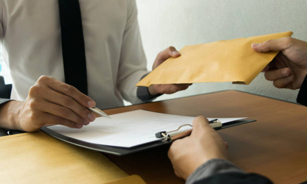 istock Cropped Hand Giving Envelope To Businessman At Table 1162949123